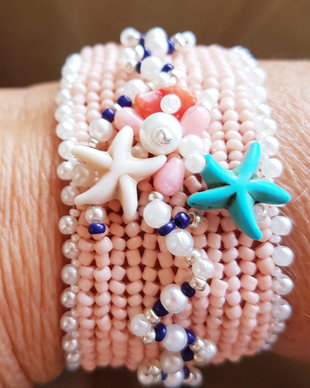 bratara unicat tip manseta din margele Toho de culoarea coralului, decorata cu stele de mare din turcoaz si howlit, margele de coral natural, perle de sticla albe si margele de sticla bleumarin
