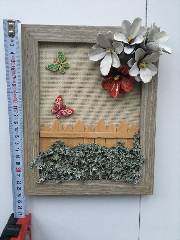 Tablou handmade pe suport de panza iuta, cu flori din conuri de pin, cu gard in miniatura din lemn de bambus, cu muschi naturali aplicati, si fluturi din lemn