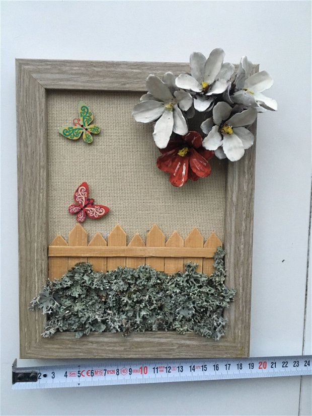 Tablou handmade pe suport de panza iuta, cu flori din conuri de pin, cu gard in miniatura din lemn de bambus, cu muschi naturali aplicati, si fluturi din lemn