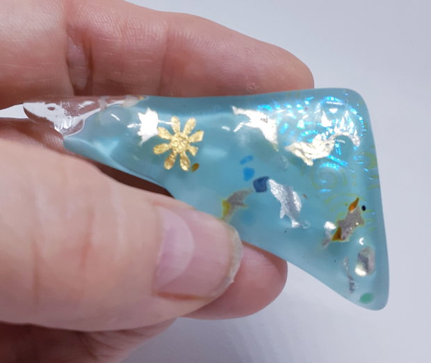 Brosa unicat, dreptunghiulara, din sticla fuzionata bleu si sticla dicroica, cu insertii delfini din argint pur si soare din foita de aur