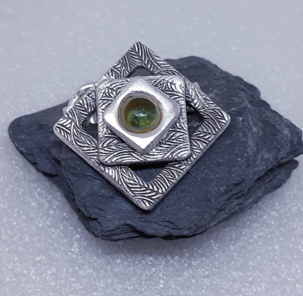 Broșă unicat din argint pur, cu design geometric compus din patrate suprapuse si un cabochon de sticla oliv