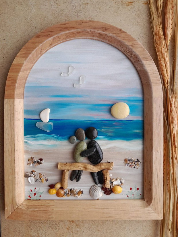 Tablou Pebble Art Cuplu pe băncuță, privind marea, bărcile și soarele, decor romantic pe lemn