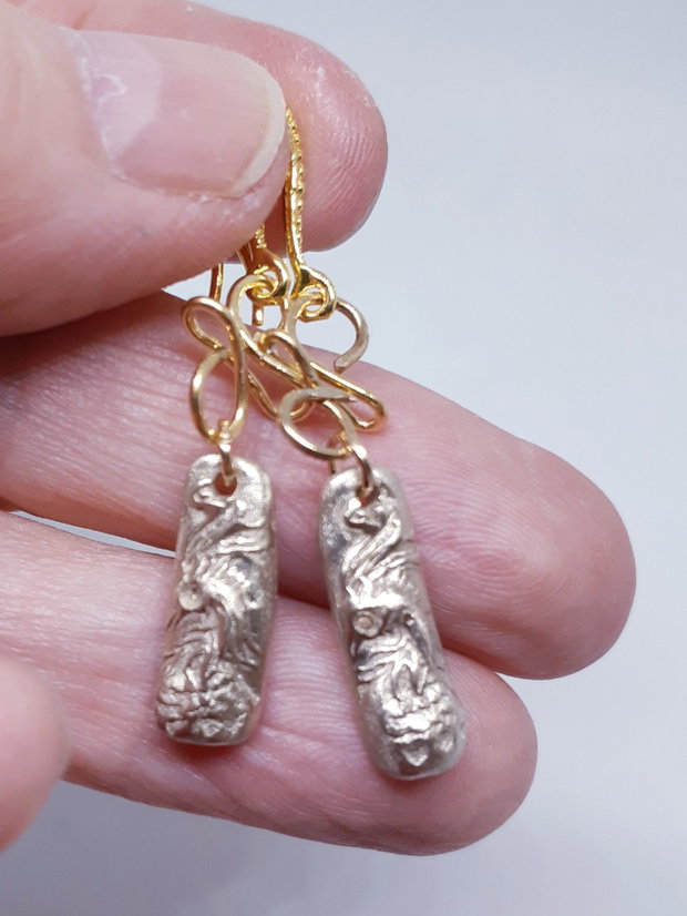 Cercei unicat din bronz, in forma de bagheta, cu un cap de phoenix cu ochi de zirconiu galben