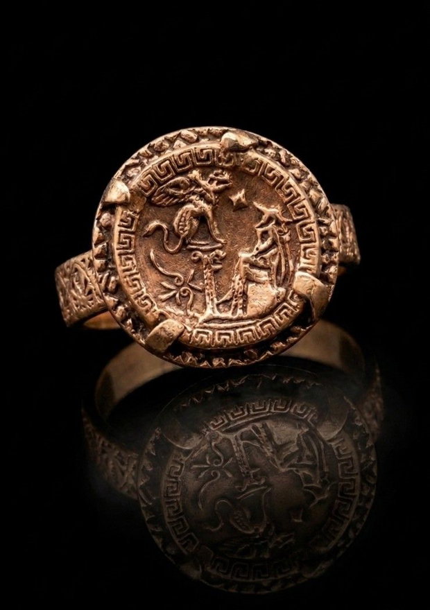 Inel unicat, din bronz, inspirat din mitologia si estetica Greciei antice, cu moneda centrala reprezentand legenda confruntarii dintre Oedip si sfinx si cu banda decorata cu un meandru